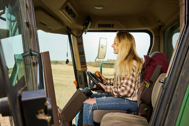 istock Young woman farmer operating a combine harvester machine on farm 1895289329
