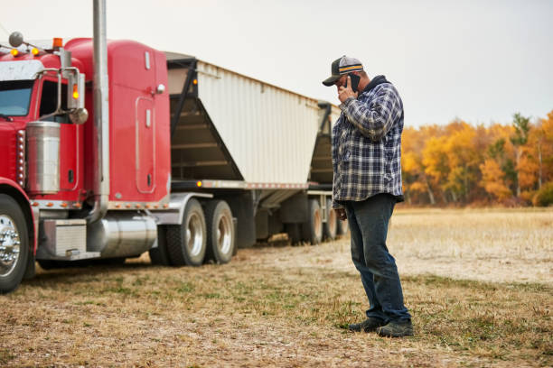 istock Farmer talking on a cellphone standing on farm with grain trailer truck 1895291410