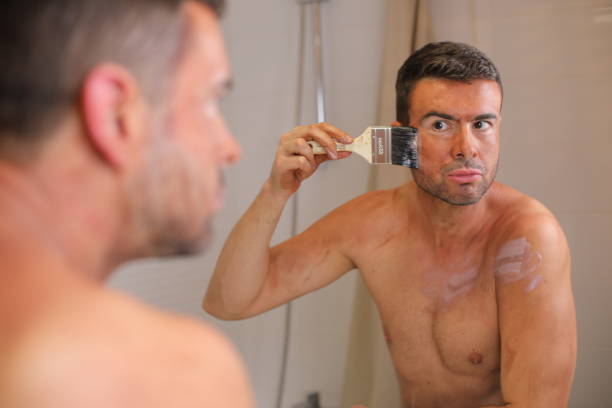 man using a lot of self tanning lotion - spray tan body human skin стоковые фото и изображения