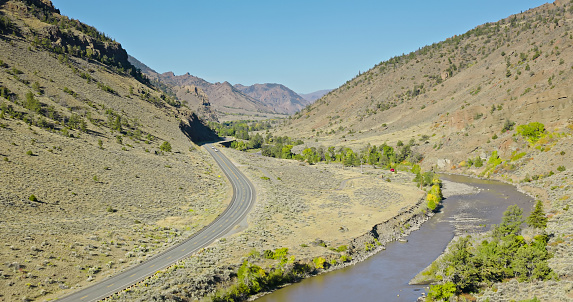Aerial still of Shoshone River and North Fork Highway in Shoshone National Forest, Wyoming, on a clear day in Fall.