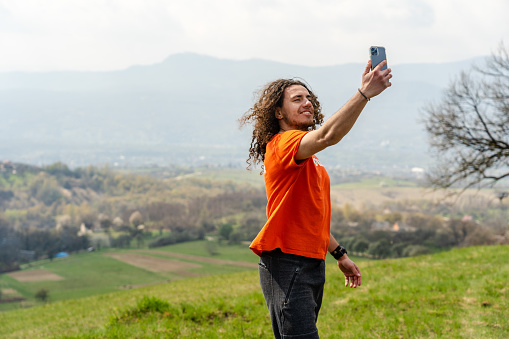 Young man making selfie on mobile phone on the hill