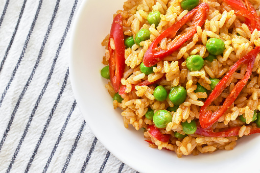 Spicy curry fried rice with sliced red chilli pepper and green peas. Healthy and dietary food. Flat lay top view photo.