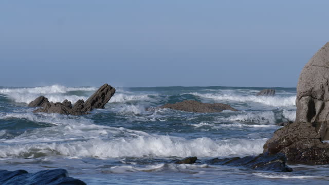 Waves hitting rocks jutting out into the sea