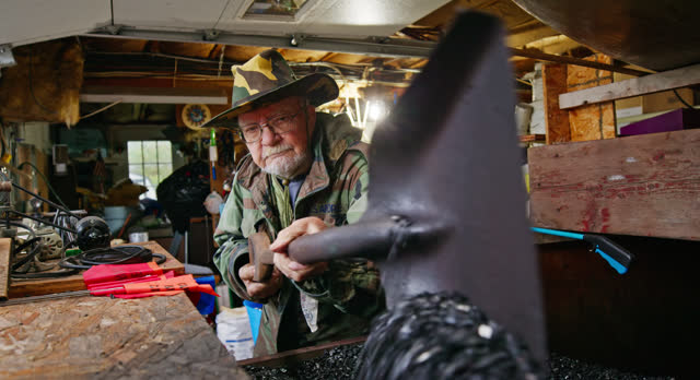 Elderly Caucasian Veteran Shoveling Coal inside his Workshop