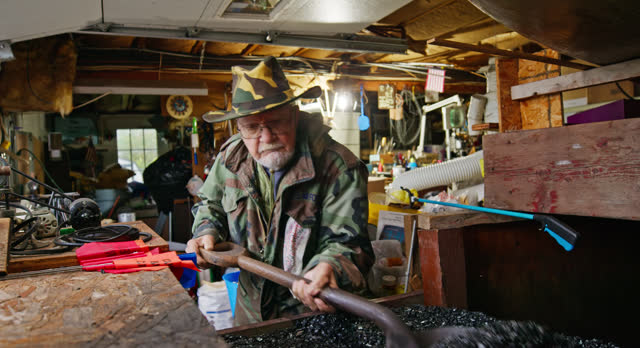 Elderly Caucasian Veteran Shoveling Coal in his Workshop