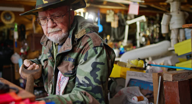Elderly Veteran Keymaker Shoveling Coal inside Workshop in Pennsylvania