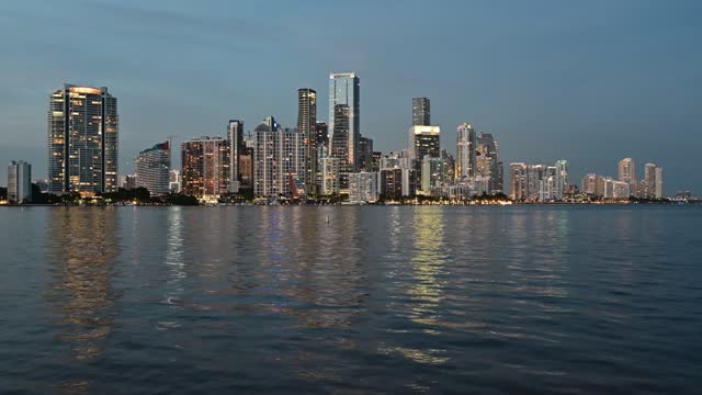 Timelapse of Miami, Florida skyline reflected in Biscayne Bay in evening twilight 4K.