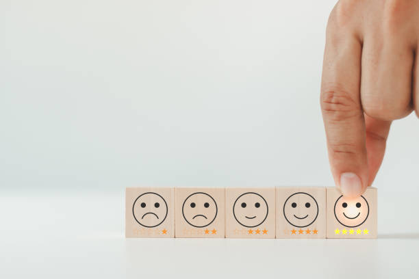 Customer service evaluation and satisfaction survey concept. The client's hand picked the happy face smile face icon and five star symbol on wooden cube. Best excellent business rating experience.