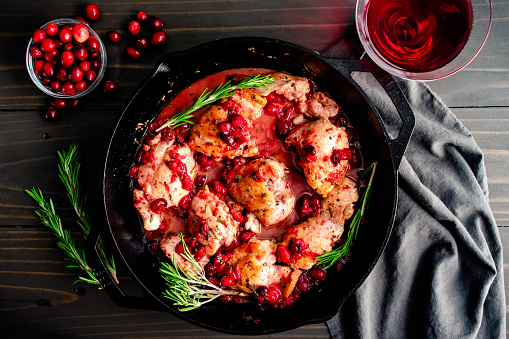 Boneless skinless chicken thighs cooked with cranberries garnished with fresh rosemary sprigs
