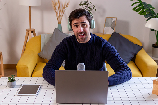 Portrait of young man in headphones using laptop while sitting at home