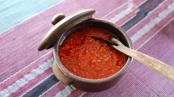 Sambal terasi served in traditional bowl. It is traditional side dish from indonesia. Made from fresh red chili and shrimp paste. Hot and delicious taste.