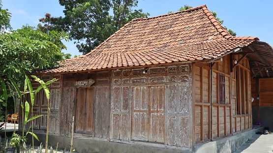 Traditional Javanese house made from wood that looks classic and luxurious with blue sky background.