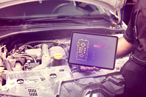 Mechanic using tablet checking up on car engines parts for fixing and repair