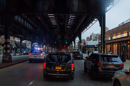 Brighton Beach Avenue in Brooklyn, New York City, USA — August, 2023: driving on Brighton Beach Avenue during rush hour under the subway line. Cars and Police force are stuck in traffic