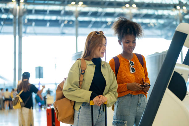 istock Two woman using self Check-in kiosk machine at airport terminal. 1895940159