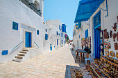 A street in Hammamet Old Medina, Tunisia. A medieval town with white walls with blue paintwork and stone pavements.
