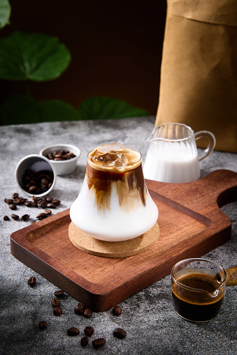 Dirty coffee and volcano shaped glass on wooden tray, professional shot indoors, studio light, dark background