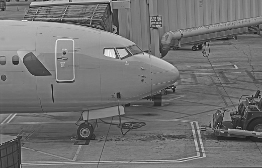 Airplane cockpit outside.   Parked at gate.   Black and white.