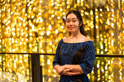 Confident Pacific Islander woman in her traditional clothing looking at camera with illuminated background.