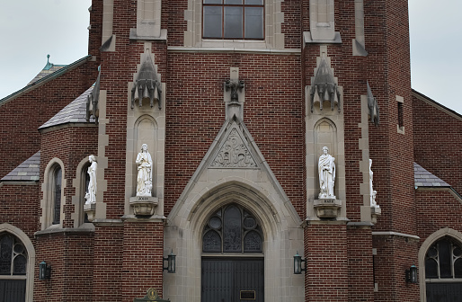The entrance to a historic church building with statuettes on either side in Covington, Kentucky