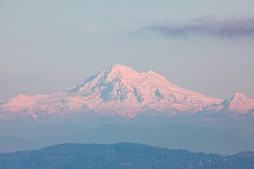 In the distance, the snow-capped summit of Mount Baker stands tall, shrouded in a pristine blanket of snow. The image captures the majestic solitude of this iconic peak, inviting viewers to immerse themselves in the tranquility of the snowy landscape.