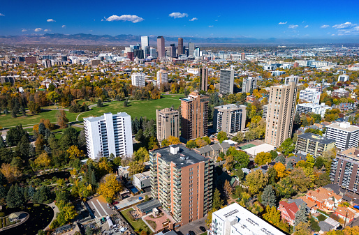 Downtown Denver skyline and the Rocky Mountains in the background with Denver's Cheesman Park neighborhood including the park itself and highrise residential buildings.