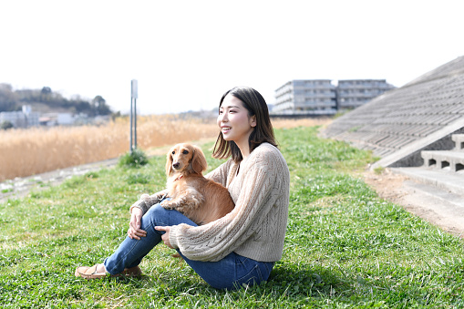 Young Asian female owner holding her pet dachshund during a walk