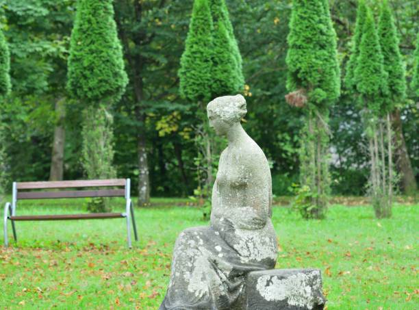 istock Decorative stone sculpture built in a garden park with bench and trees 1896571094