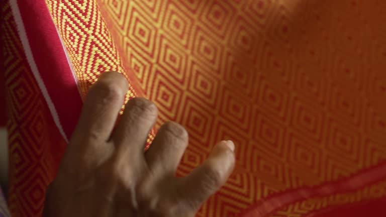 woman's hand touches a local hand-woven cotton cloth