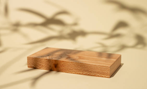 istock Empty wooden board with shadows and green leaves on a yellow background with shadow. 1896574043