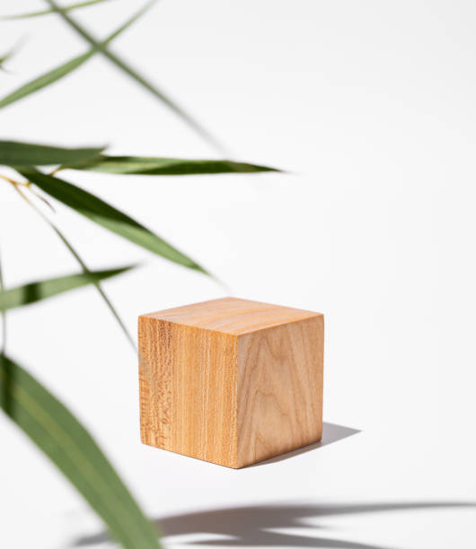 istock Empty wooden cube with shadows and green leaves on a white background. 1896574227