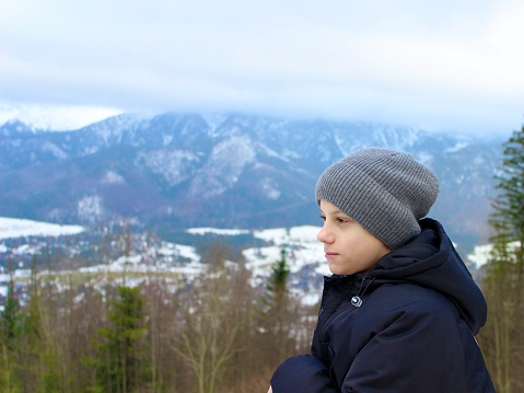 A boy in a hat against the background of snowy mountains
