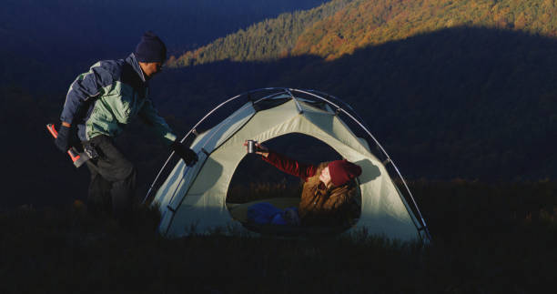 istock Man sets up tent on top of mountain hill using axe 1896671819