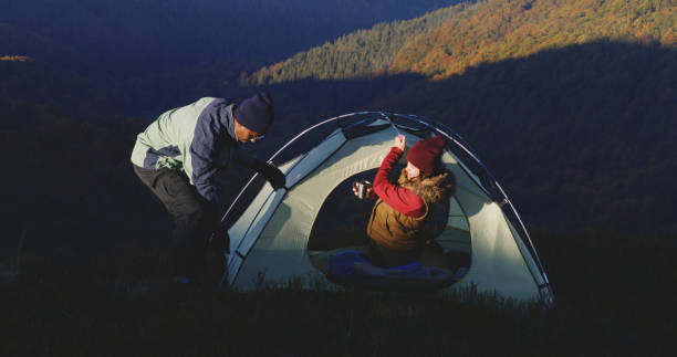 istock Man sets up tent on top of mountain hill using axe 1896673884