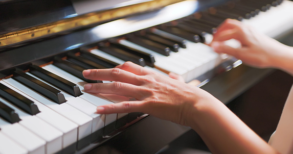 Woman's hands playing on the keyboard of the piano in night closeup