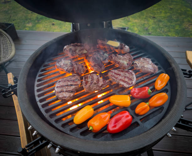 istock Large kamado type barbeque grill with filet mignon steaks and vegetables cooking and flames coming out 1896764367