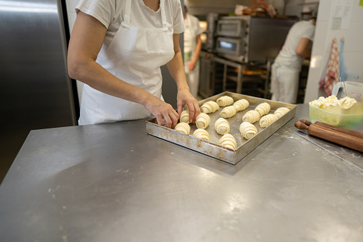 Unrecognizable woman putting stuffed pastry on the tray before baking