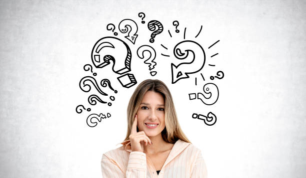 istock Young woman with smiling look, question marks on grey concrete wall 1896813635