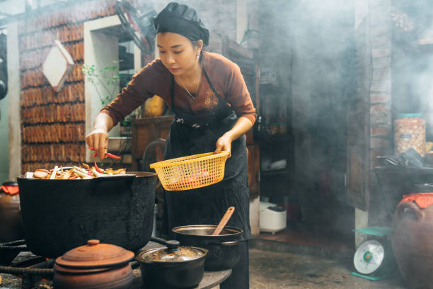 istock vietnamese woman cooking steamed fish on open fire in restaurant 1896813734