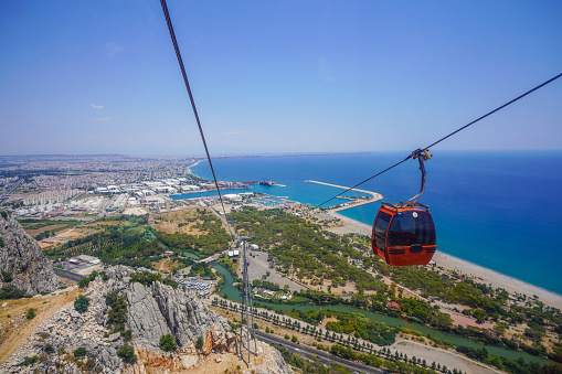 Cable car cabin close-up rides over a bright panorama of Antalya (Turkey). Beautiful seascape of Turkish Riviera from cable car, aerial view.