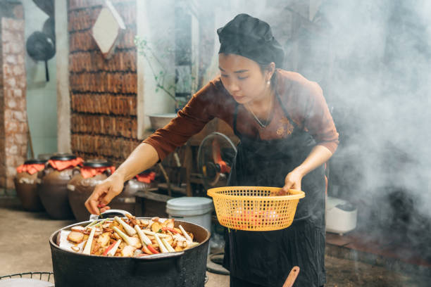 istock vietnamese woman cooking steamed fish on open fire in restaurant 1896813746