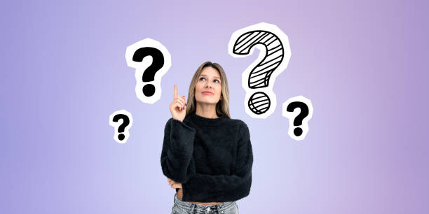 istock Pensive young woman smiling and looking up at question marks in row 1896813930