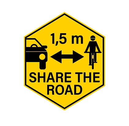 Share the road, pass cyclists safely and keep safety distance. Warning yellow hexagon sign, with car passing a person on a bicycle.