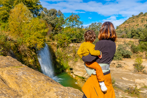 Mother with a son at the Vero river waterfall in the town of Pozan de Vero in the Pyrenees, Huesca