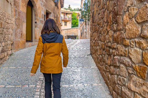 A woman walking through the streets of the Pyrenean village of Alquezar, medieval town of Huesca, Spain