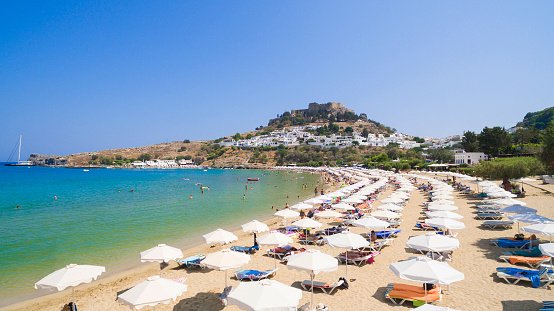 View of sandy beach in Bay of Lindos, Acropolis in background (Rhodes, Greece)