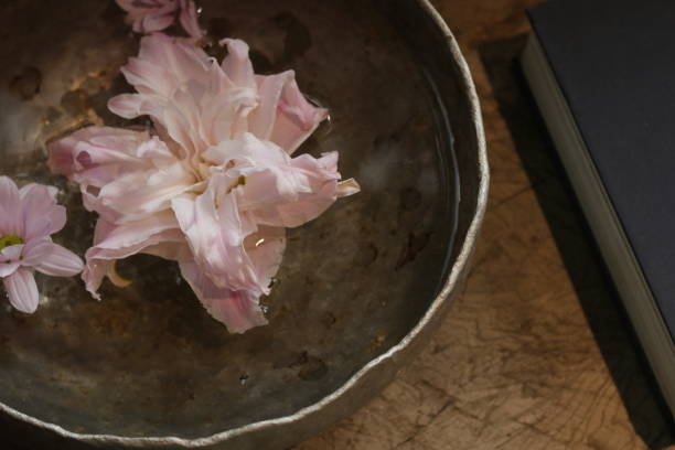 Aluminum basin, water, flowers, table. Pink flowers float above aluminum pots.