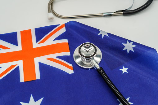 A professional stethoscope perched on a vibrant Australian flag, a symbol of the country's strong healthcare system. Medical services and the quality of health care in Australia.