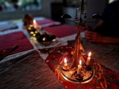 traditional Christmas table with a metal tree and candles spins the merry-go-round with hot air. tinkling carillon. dropping a candle shell in a bowl of water is a tradition, tinkling, carlion