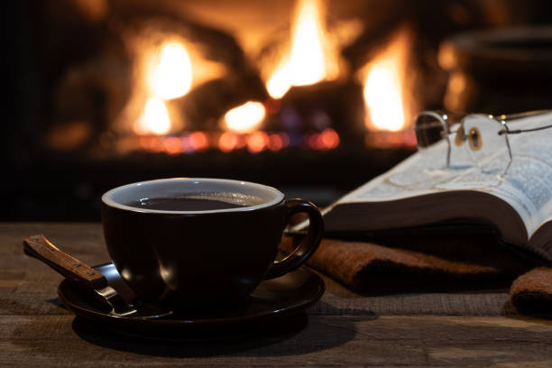 istock Cup of coffee with burning fireplace in background 1897192654